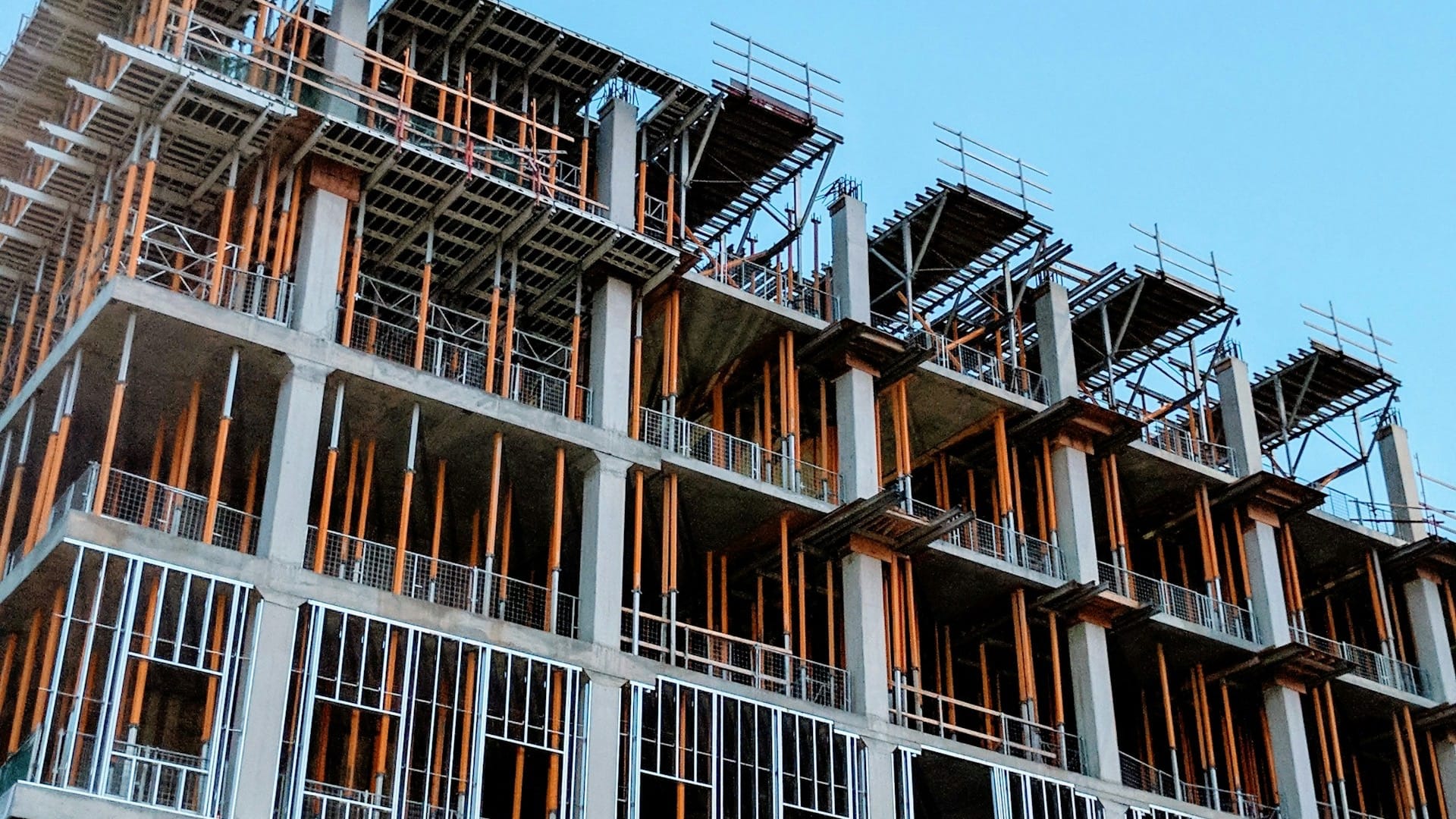 A concrete building under construction, its floors and orange support props exposed before the walls go up