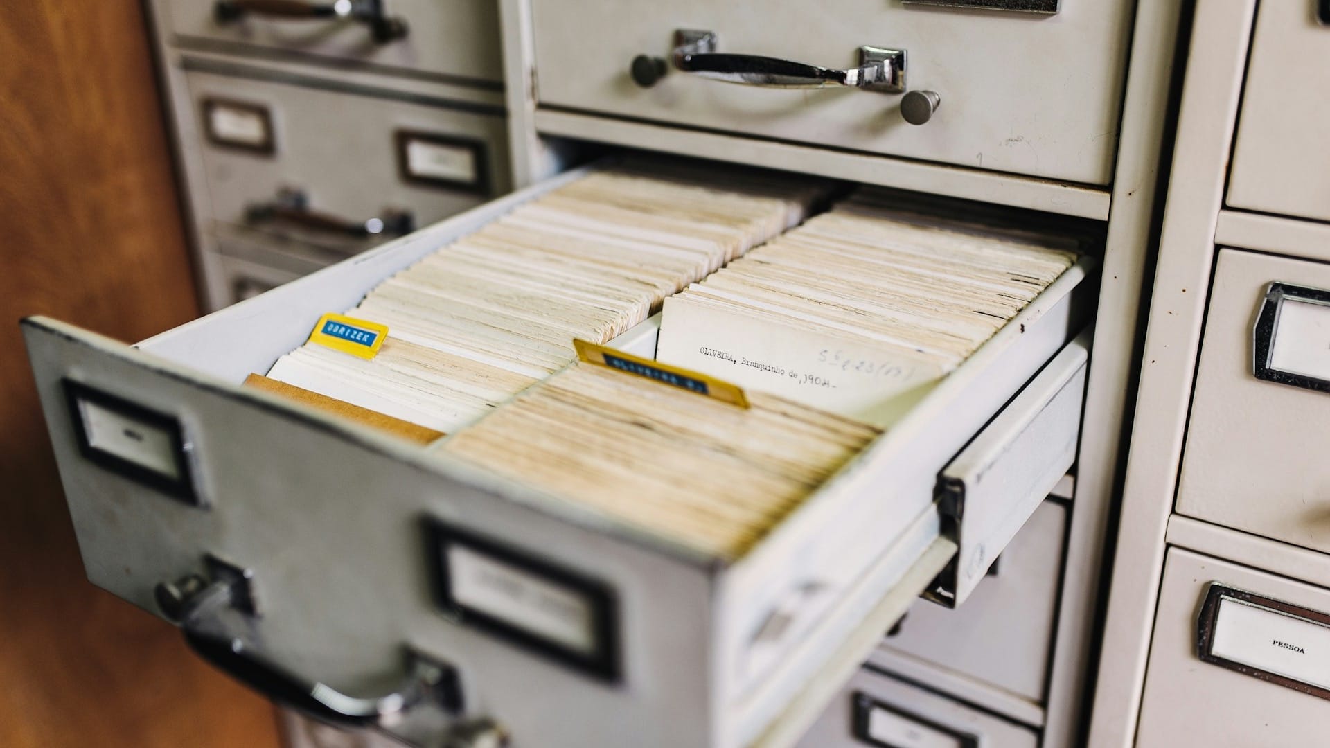 An open drawer of an old filing cabinet, packed with handwritten index cards someone else catalogued