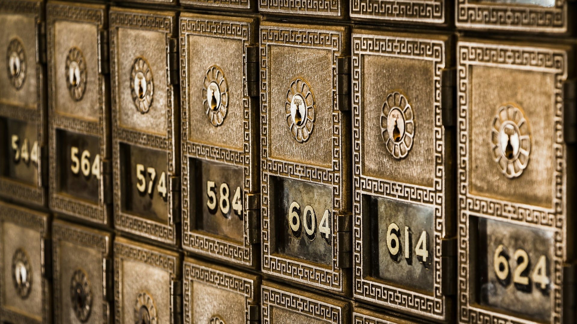 A wall of numbered metal safe deposit boxes in a bank vault