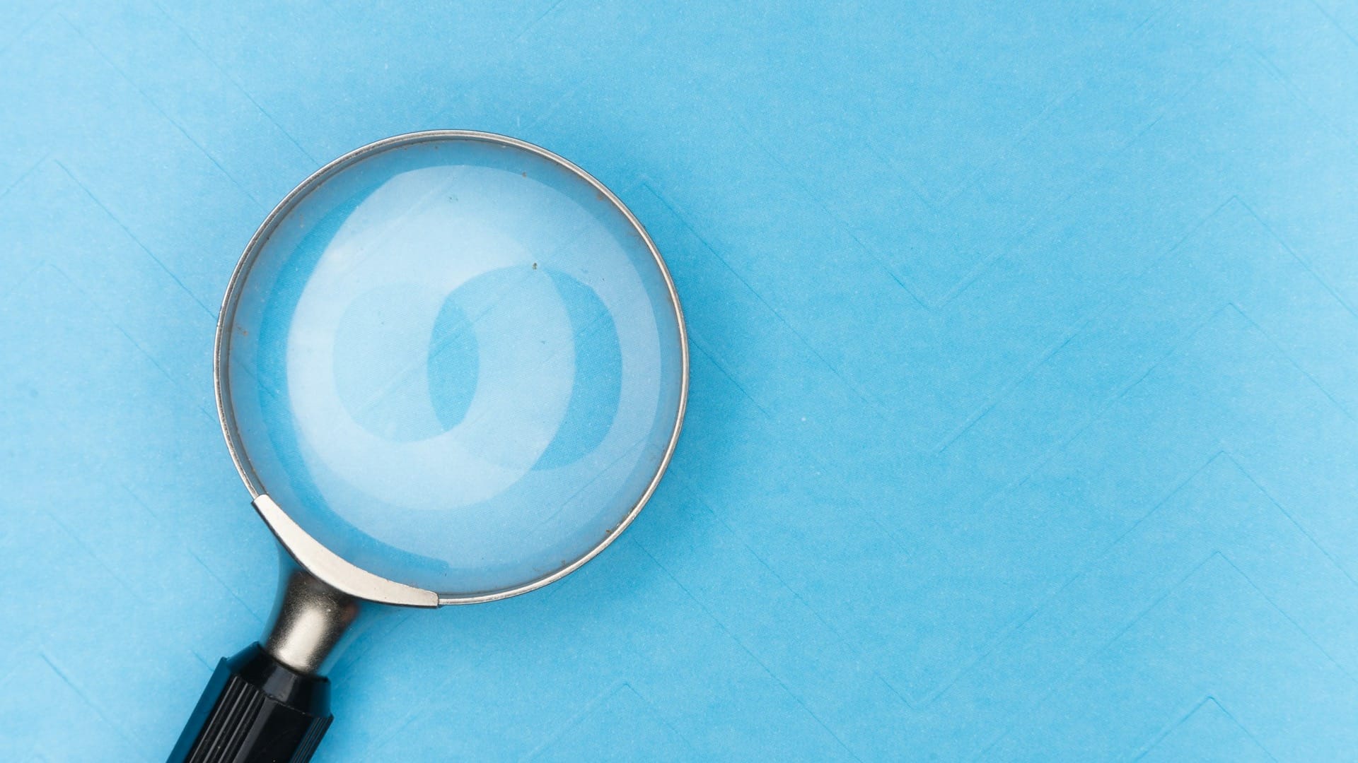 A magnifying glass resting on a plain white surface