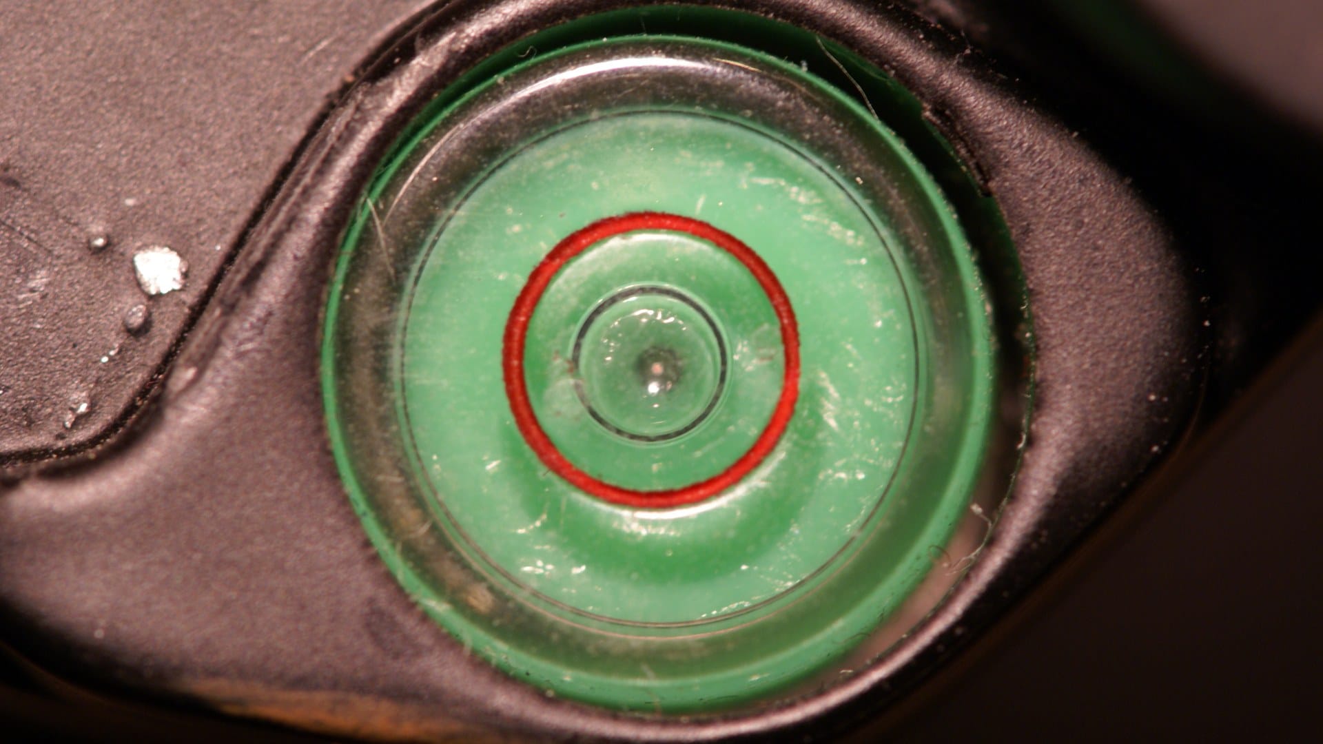 Close-up of a green bull's-eye spirit level with the bubble centred inside the red ring.