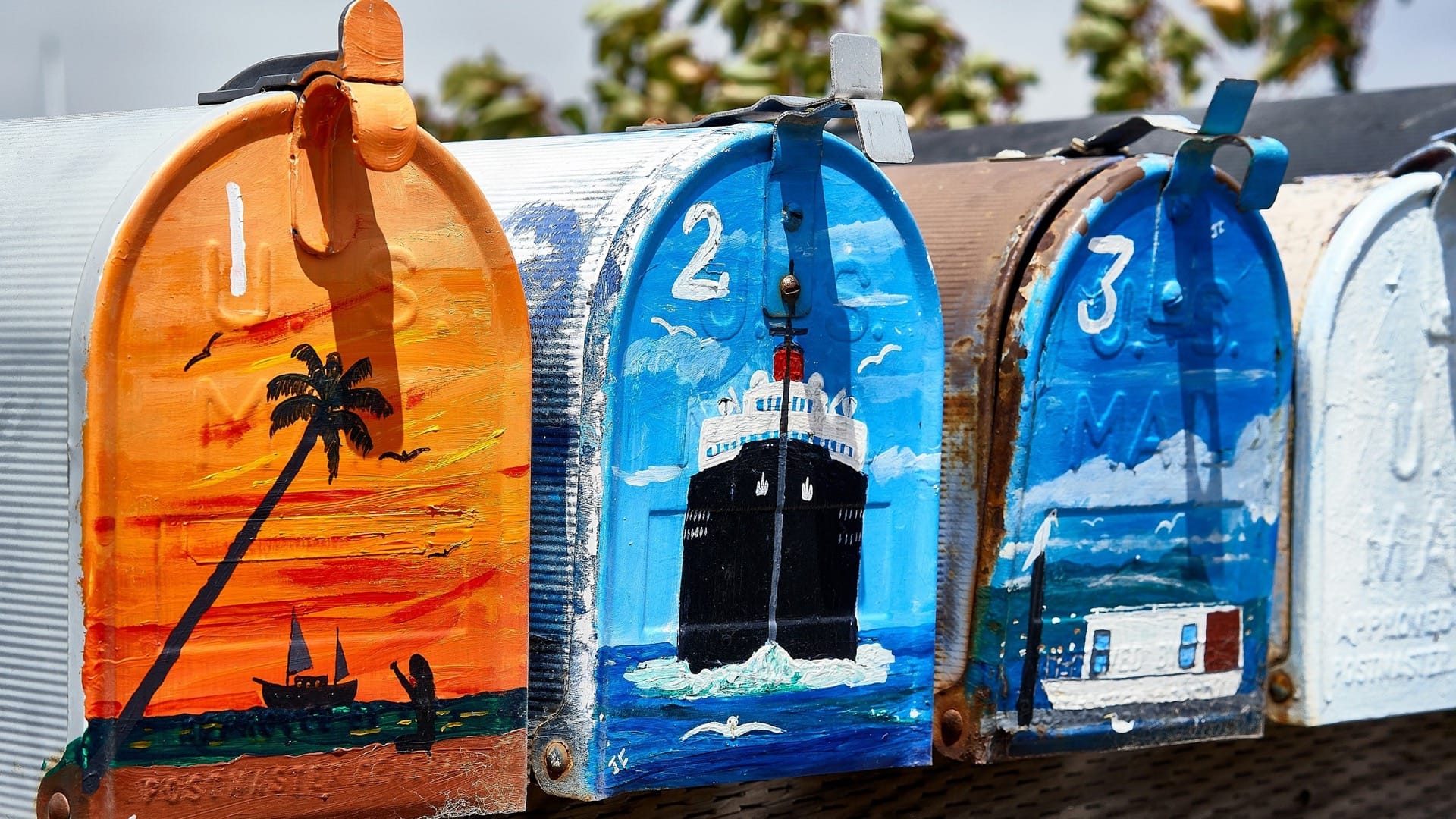 Numbered mailboxes painted with colourful seaside scenes stand side by side.