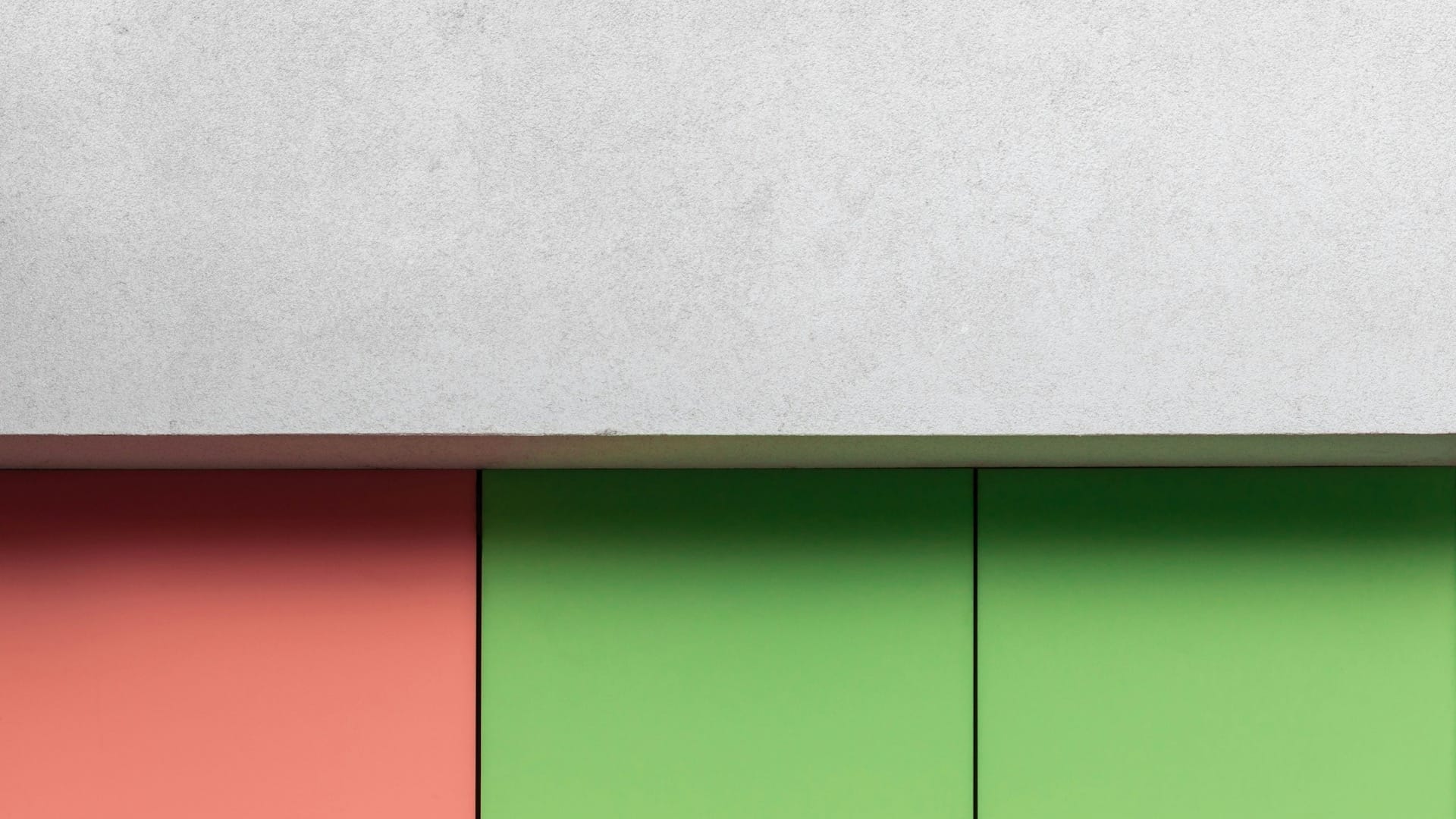 Green and coral facade panels beneath a pale textured concrete wall.