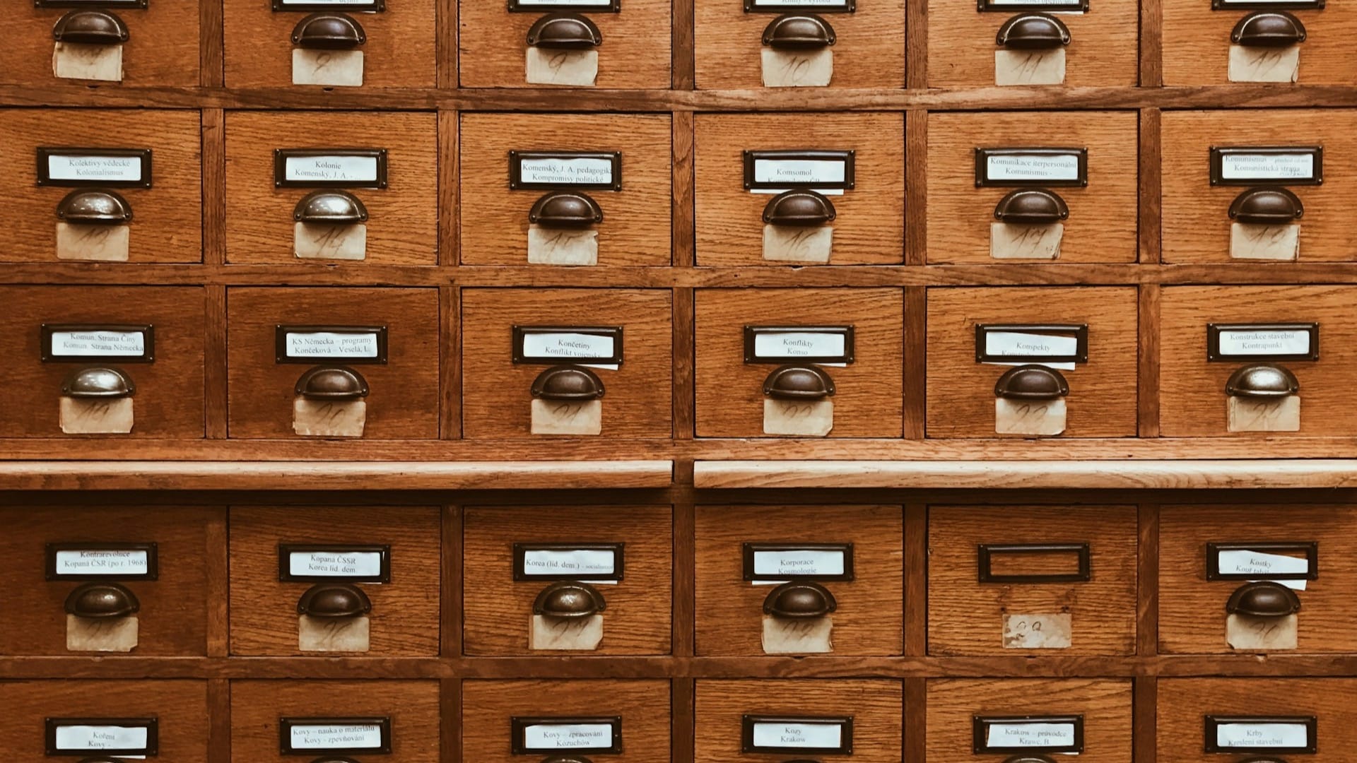 Rows of wooden library catalogue drawers with brass handles and paper labels.
