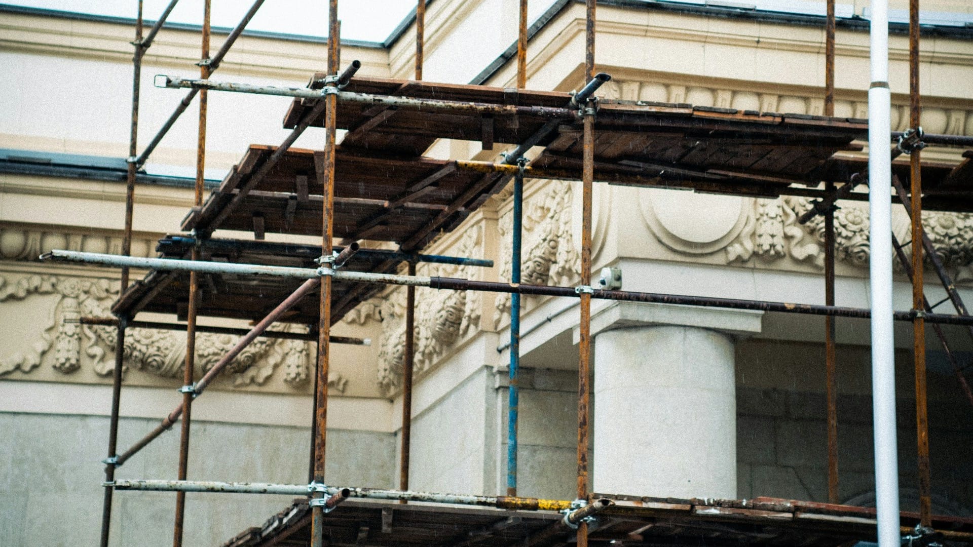 Scaffolding surrounds the columns and carved facade of a building being renovated.